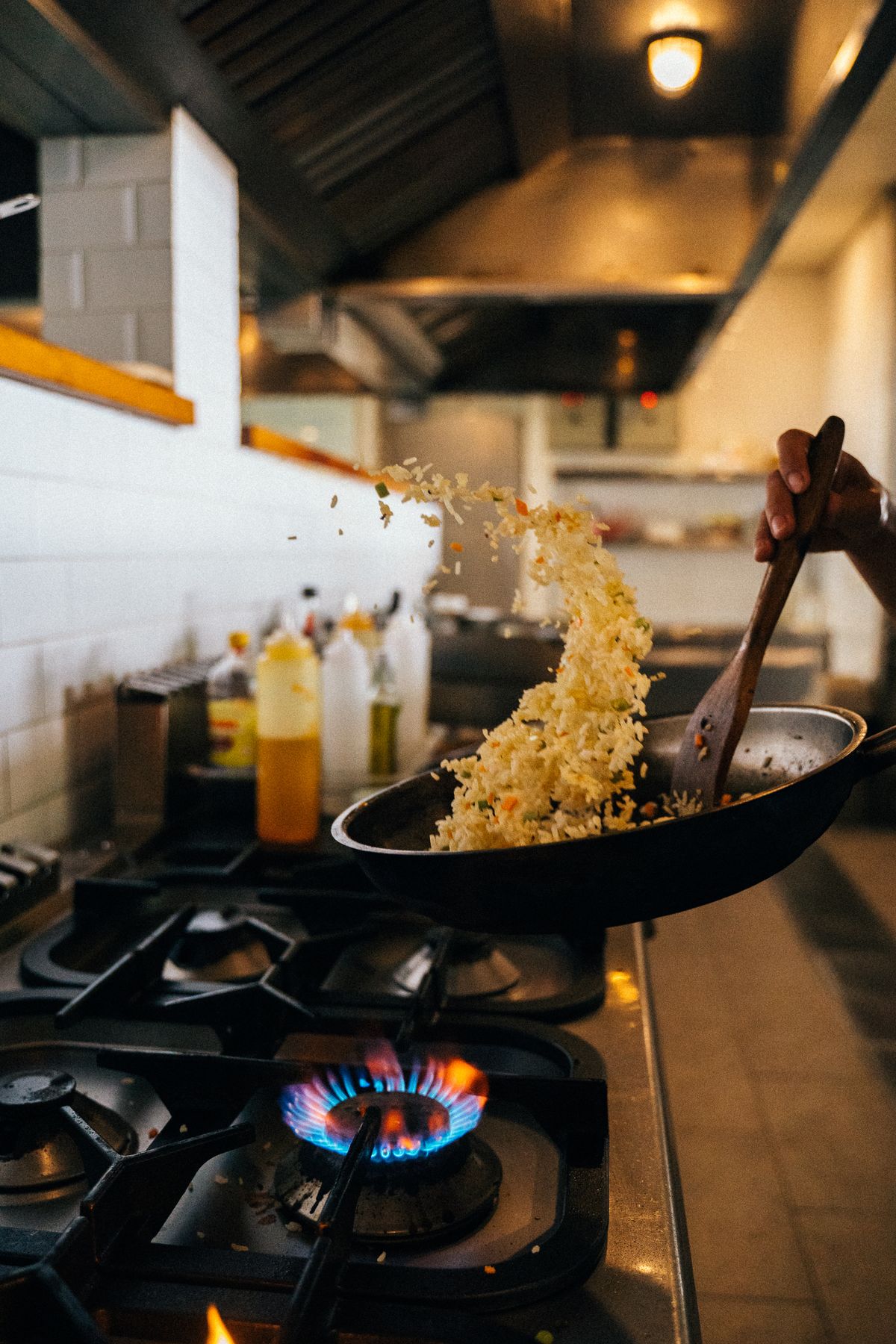 A chef tossing fried rice in a hot wok